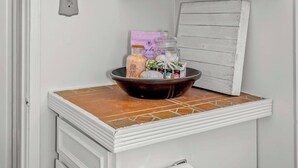 Ein Badezimmer mit einem weißen Schrank, gefalteten Handtüchern, einer kleinen Ablagefläche für Toilettenartikel und einer gefliesten Spüle.