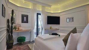 A modern bedroom with a large bed, a flat-screen TV, a desk with a chair, and a potted cactus. - ThaoDien Boutique Hotel (Ho Chi Minh City)
