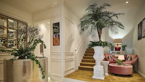 A spacious foyer with a staircase, a large potted plant, a seating area with a lamp, and a decorative mirror. - ThaoDien Boutique Hotel (Ho Chi Minh City)