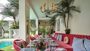 A dining area with a pool view, red seating, and potted plants. - ThaoDien Boutique Hotel (Ho Chi Minh City)