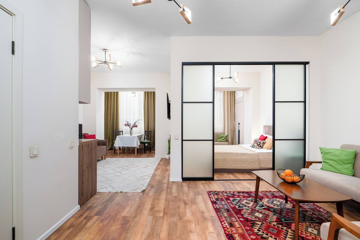 Una sala de estar moderna con suelo de madera, un sofá, una mesa de centro y un comedor con mesa y sillas.