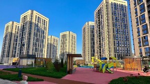 A modern residential area with high-rise apartment buildings, a playground, and a paved walkway. - Business Aparts near MEGA Almaty  (Almaty)