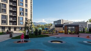 A playground with circular play areas and a building with balconies in the background. - Business Aparts near MEGA Almaty  (Almaty)