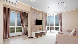 A modern living room with large windows, a flat-screen TV, a fireplace, and a sofa. - Business Aparts near MEGA Almaty  (Almaty)