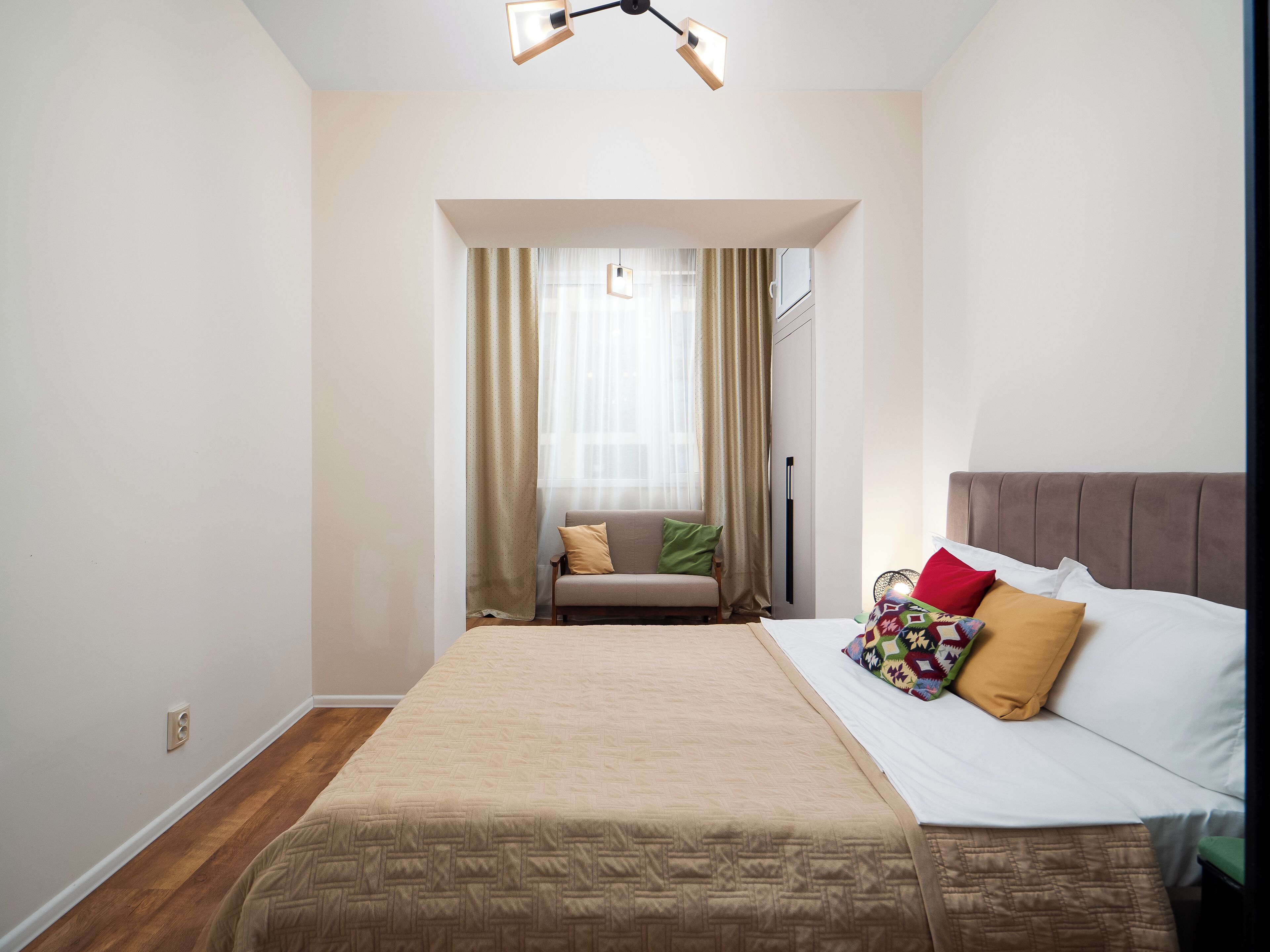 A bedroom with a bed, a sofa, and a window with curtains.
