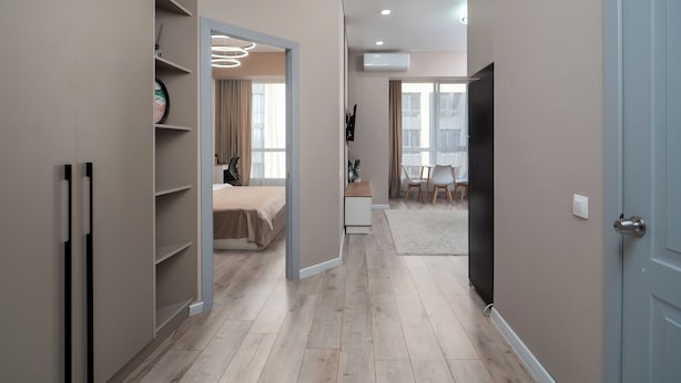A modern hotel room with a wooden floor, a bed, a desk, and a TV. - Business Aparts near MEGA Almaty  (Almaty)