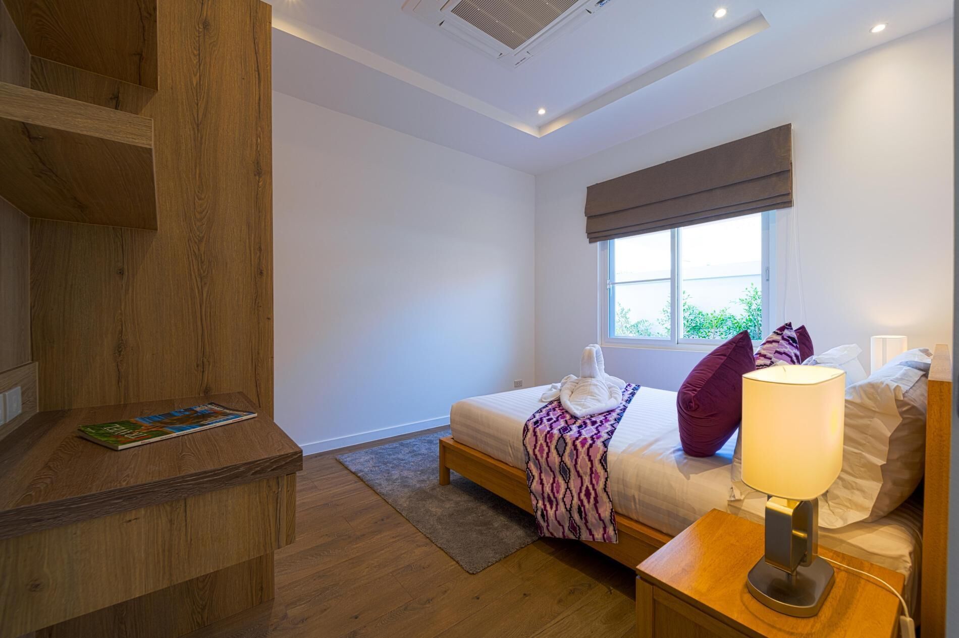 Une chambre à coucher avec un lit, une table de chevet avec une lampe, une fenêtre donnant sur un beau paysage et un escalier en bois.