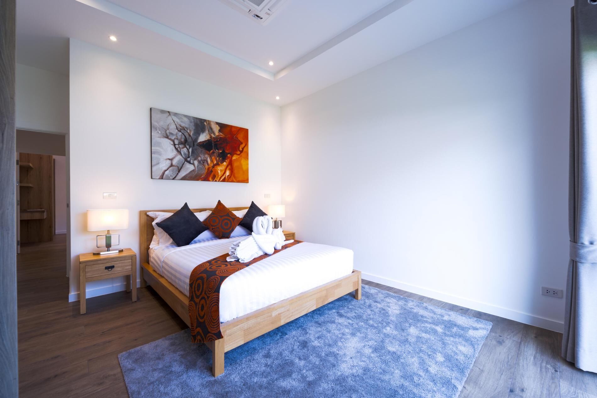A modern hotel room with a wooden bed, a blue carpet, and a painting on the wall.