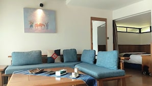 A modern living room with a sectional sofa, a wooden coffee table, and a painting on the wall.