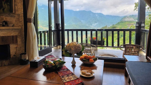A room with a wooden table, a fireplace, and a view of mountains.