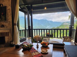 Una habitación con una mesa de madera, una chimenea y vistas a las montañas.