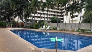 Une piscine dotée d’un poste de surveillance pour les sauveteurs, de chaises longues et d’une zone autour de la piscine bordée de palmiers.