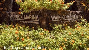 Un mur de pierre avec des panneaux indiquant l’emplacement du Waikiki Marina A, un hôtel en copropriété.