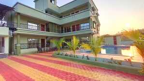 A multi-story building with balconies, a swimming pool, and a patterned pavement. - Beach Aura by Lavika Stays (Alibag)