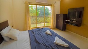 A hotel room with a bed, a TV, a wardrobe, and a balcony with a view. - Beach Aura by Lavika Stays (Alibag)