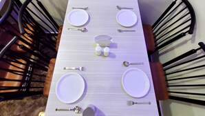 A dining table set with white plates, cutlery, and salt and pepper shakers. - Beach Aura by Lavika Stays (Alibag)
