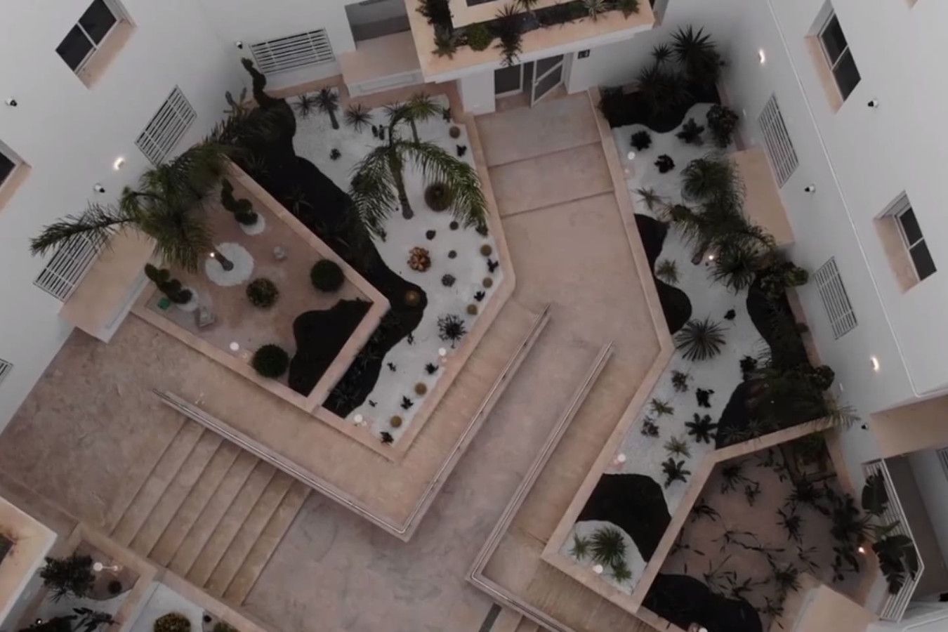 Un atrium de diversos nivells amb una escala central, envoltat d'àrees d'seure diverses i petites jardineres.