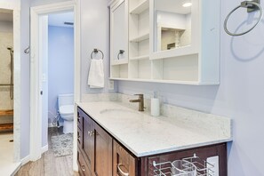 A bathroom with a marble sink, wooden cabinets, a large mirror, and a towel rack. - Mountain-View Retreat w/ Hot Tub in Centerville! (Centerville)