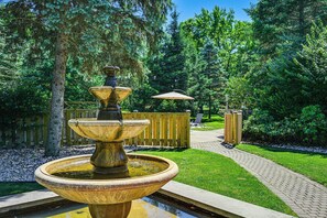 A multi-tiered fountain in a park with a wooden fence, a paved walkway, and a bench. - Pet Friendly: Private Pool & Home Theater (Buchanan)