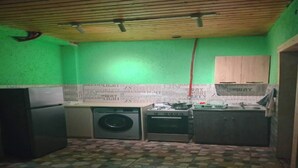 Une cuisine de taille réduite équipée d’un lave-linge, d’une cuisinière et de placards.