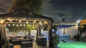 Een overdekt terras met een zithoek, lichtslingers en een kleine tafel.