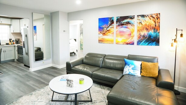 Een moderne woonkamer met een leren bank, een salontafel en een keuken op de achtergrond.