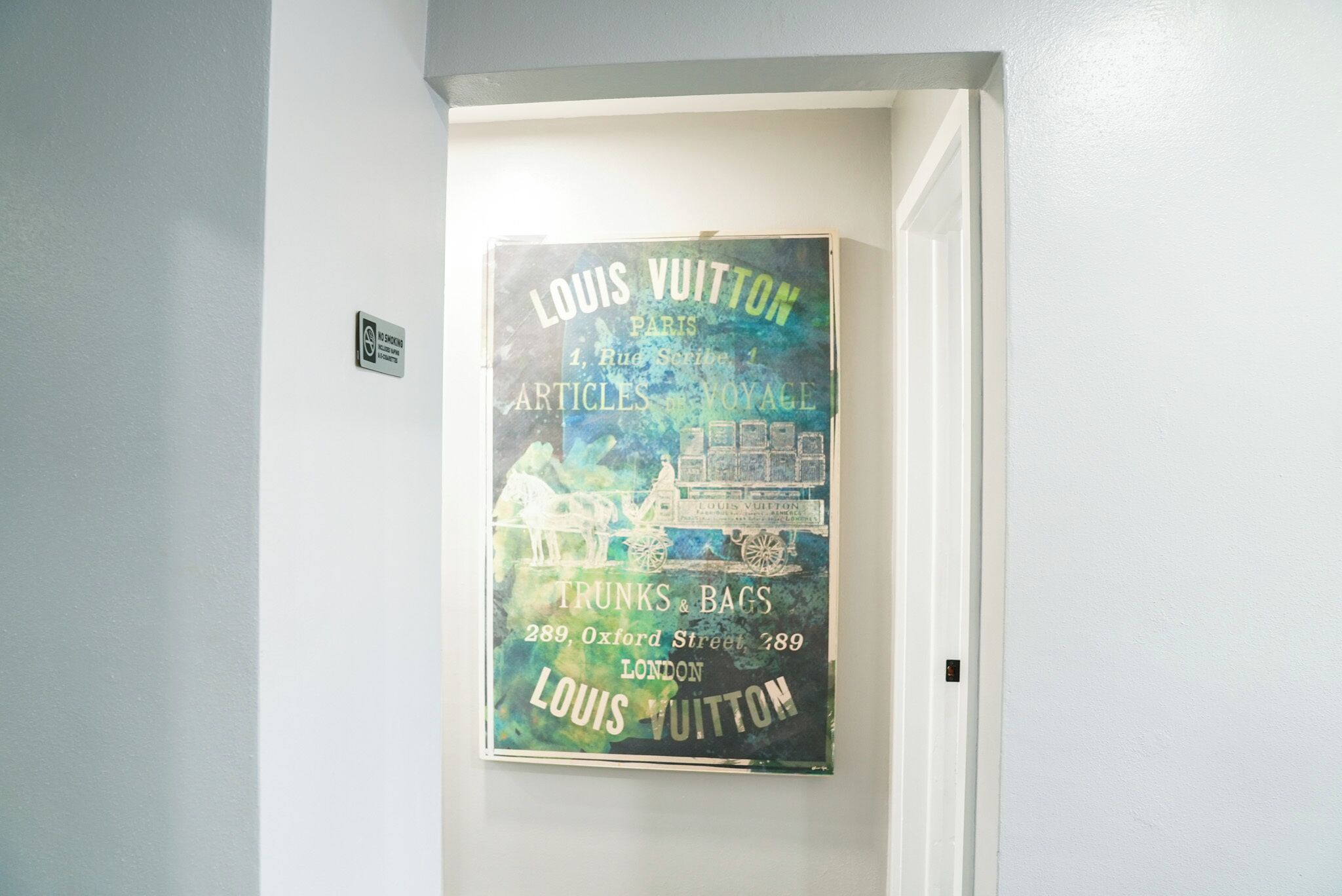Ein Poster an einer Wand wirbt für Louis Vuitton und gibt die Adresse 289 Oxford Street, London an.