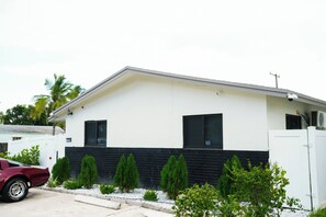 Une maison moderne à deux étages, dotée d’une façade blanche et de détails noirs, avec une allée et une voiture garée.