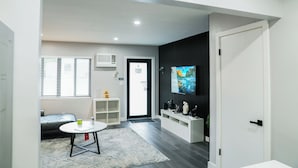 Een moderne woonkamer met een bank, een salontafel en een aan de muur bevestigde televisie.