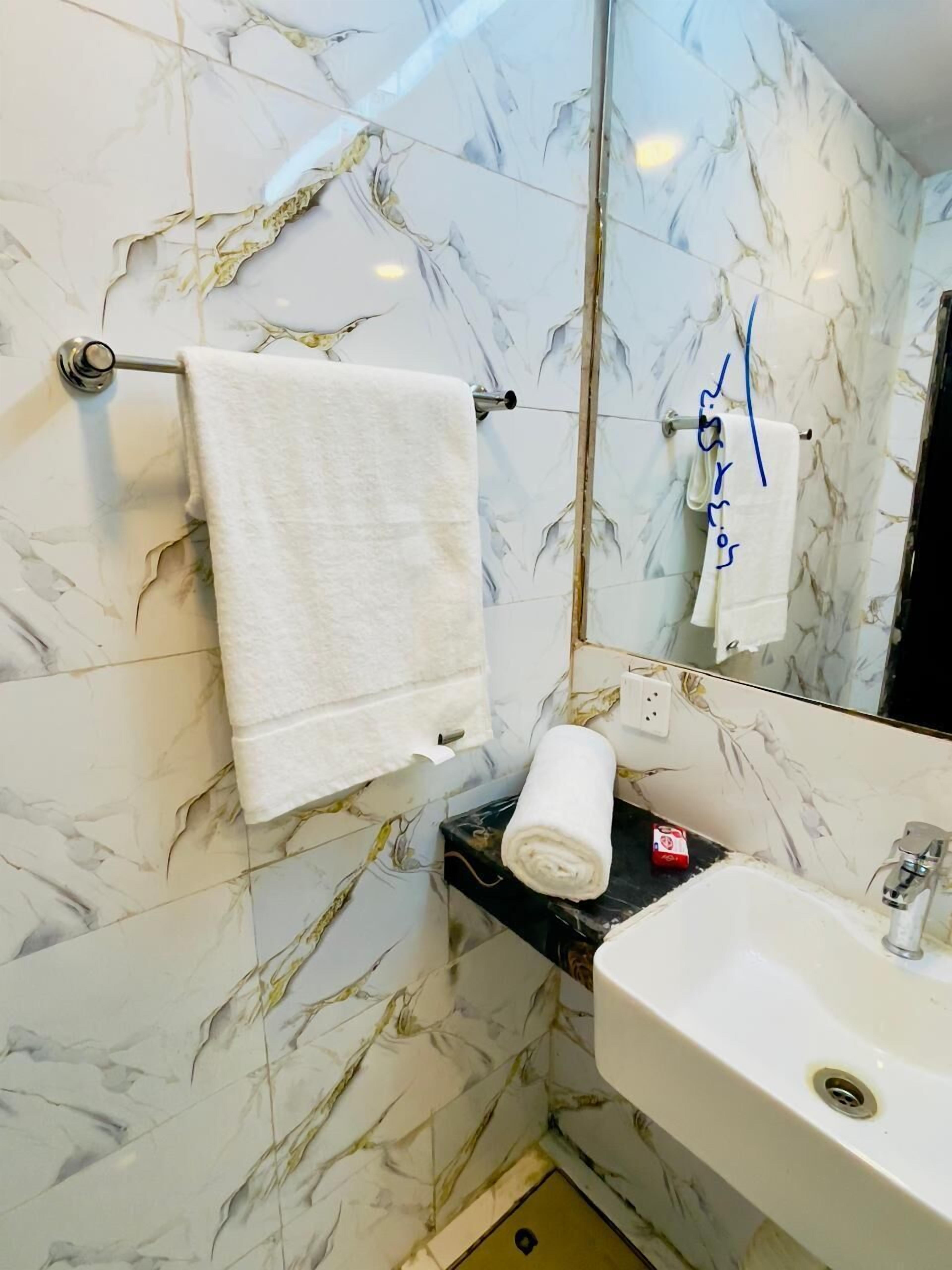 A bathroom with marble walls, a white sink, and a towel rack.