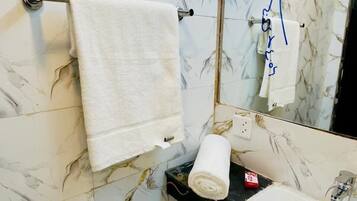 A bathroom with marble walls, a white sink, and a towel rack.