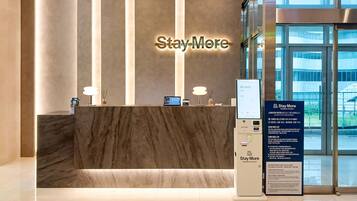 A reception desk with a 'Stay More' sign, a digital screen, and a directory board.