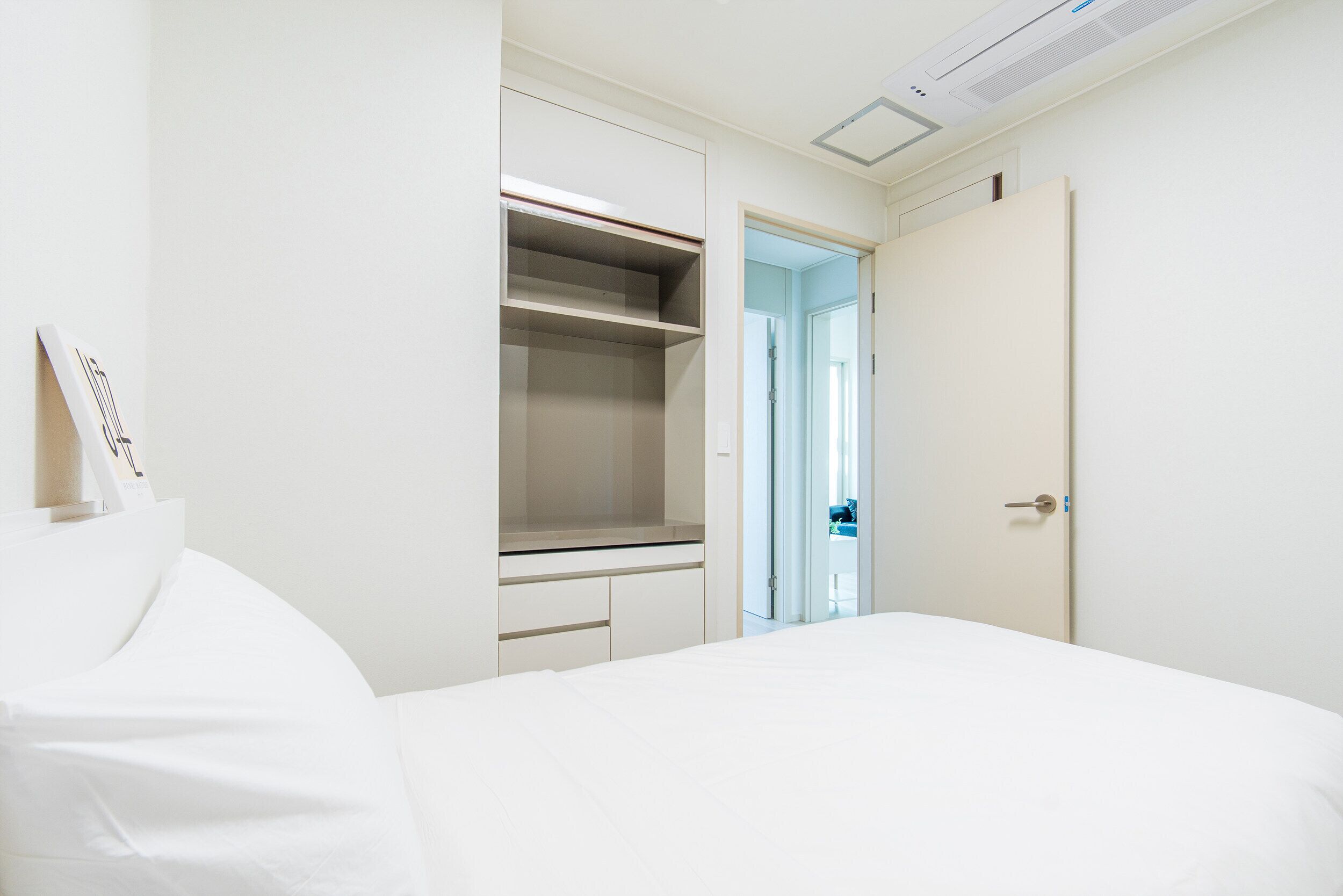 A bedroom with a bed, a wardrobe, and a door leading to another room.