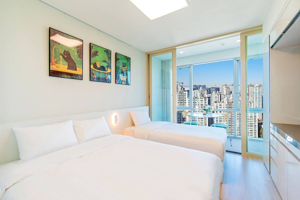 Habitación de hotel con dos camas, vistas a la ciudad y obras de arte en la pared.