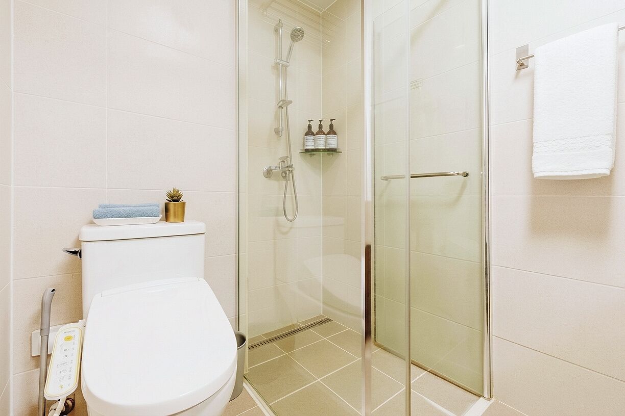 Un baño con inodoro, cabina de ducha de cristal y barra para toallas.
