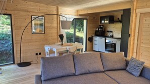 Een gezellig interieur van een blokhut met een bank, een eettafel en een keukenhoek.
