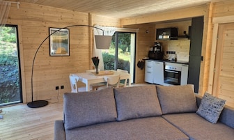Interior acogedor de una cabaña con sofá, mesa de comedor y zona de cocina.