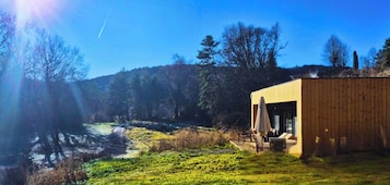 Una cabaña moderna de madera con un espacio de patio, rodeada por un paisaje boscoso.
