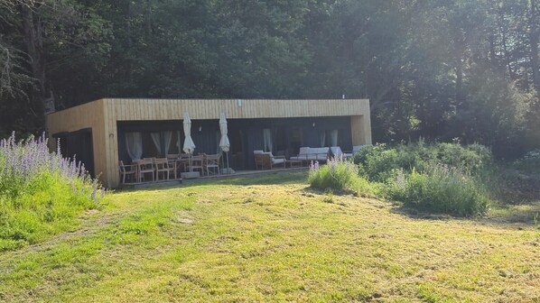 A modern wooden building with outdoor seating and a garden. - Les Ecolodges du Lac (Chambon-sur-Lac)