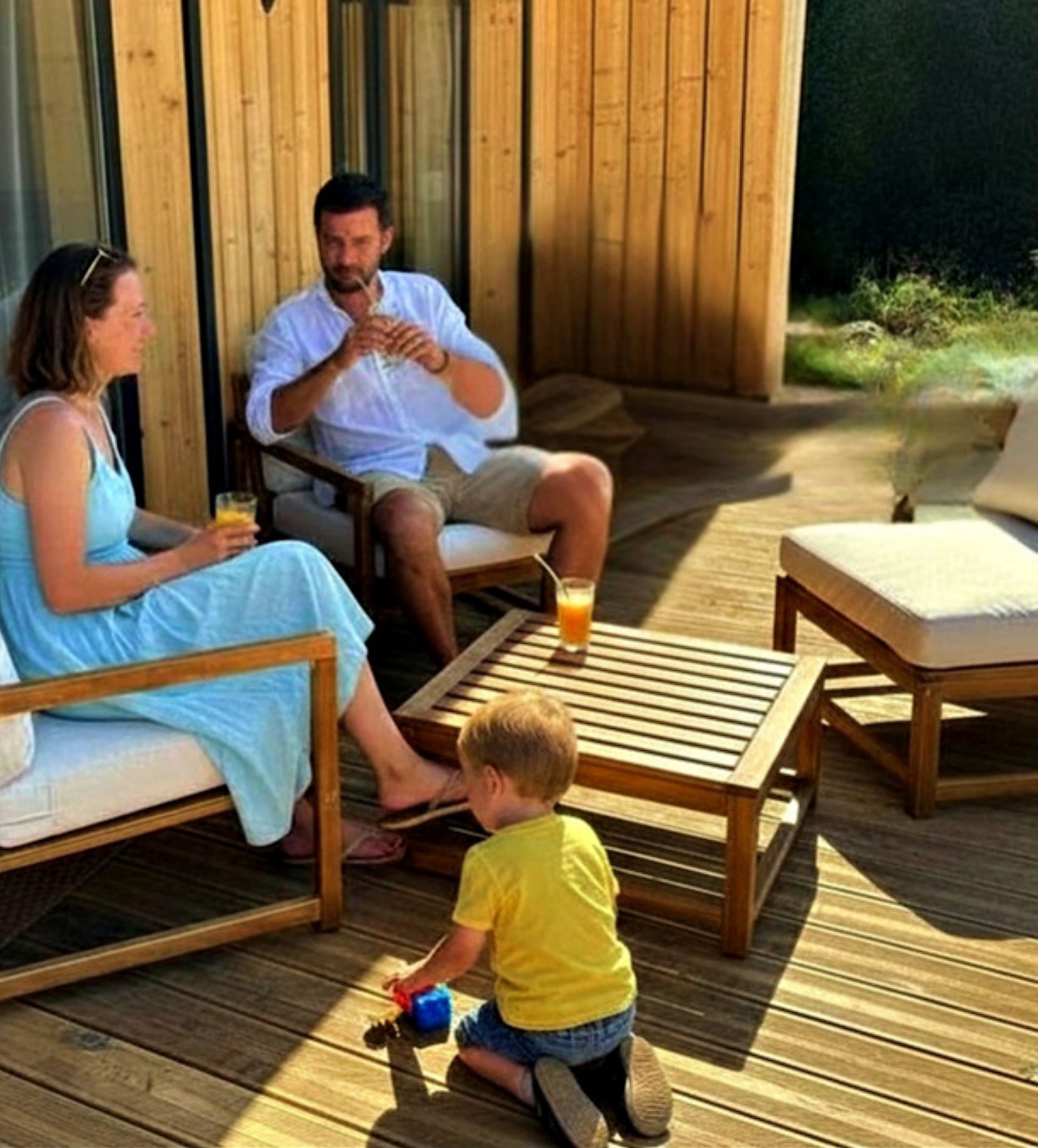 A wooden deck with outdoor furniture, including a sofa and a table.