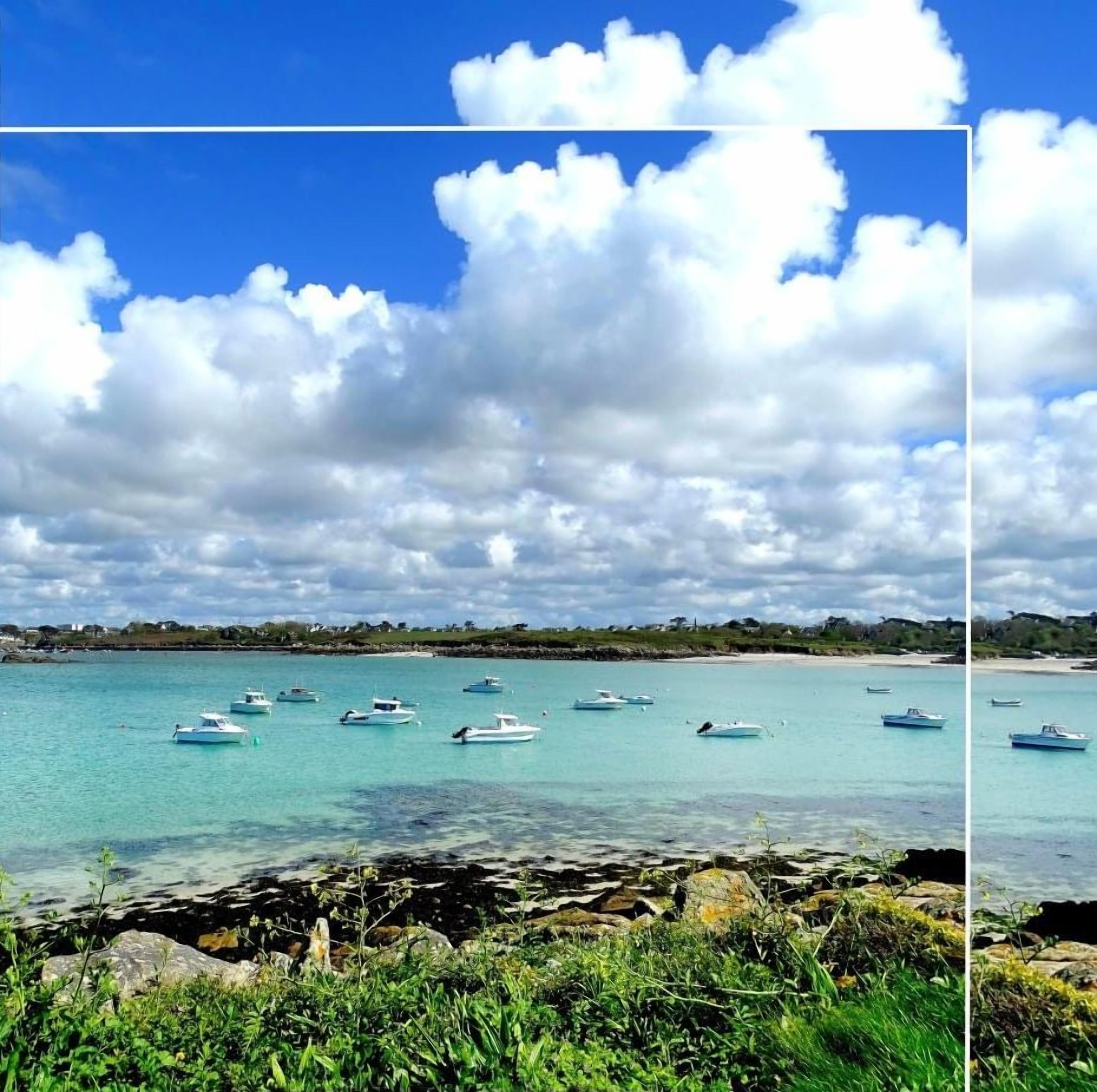Une vue sur la côte, avec des bateaux sur une eau turquoise, un rivage rocheux et une végétation luxuriante.