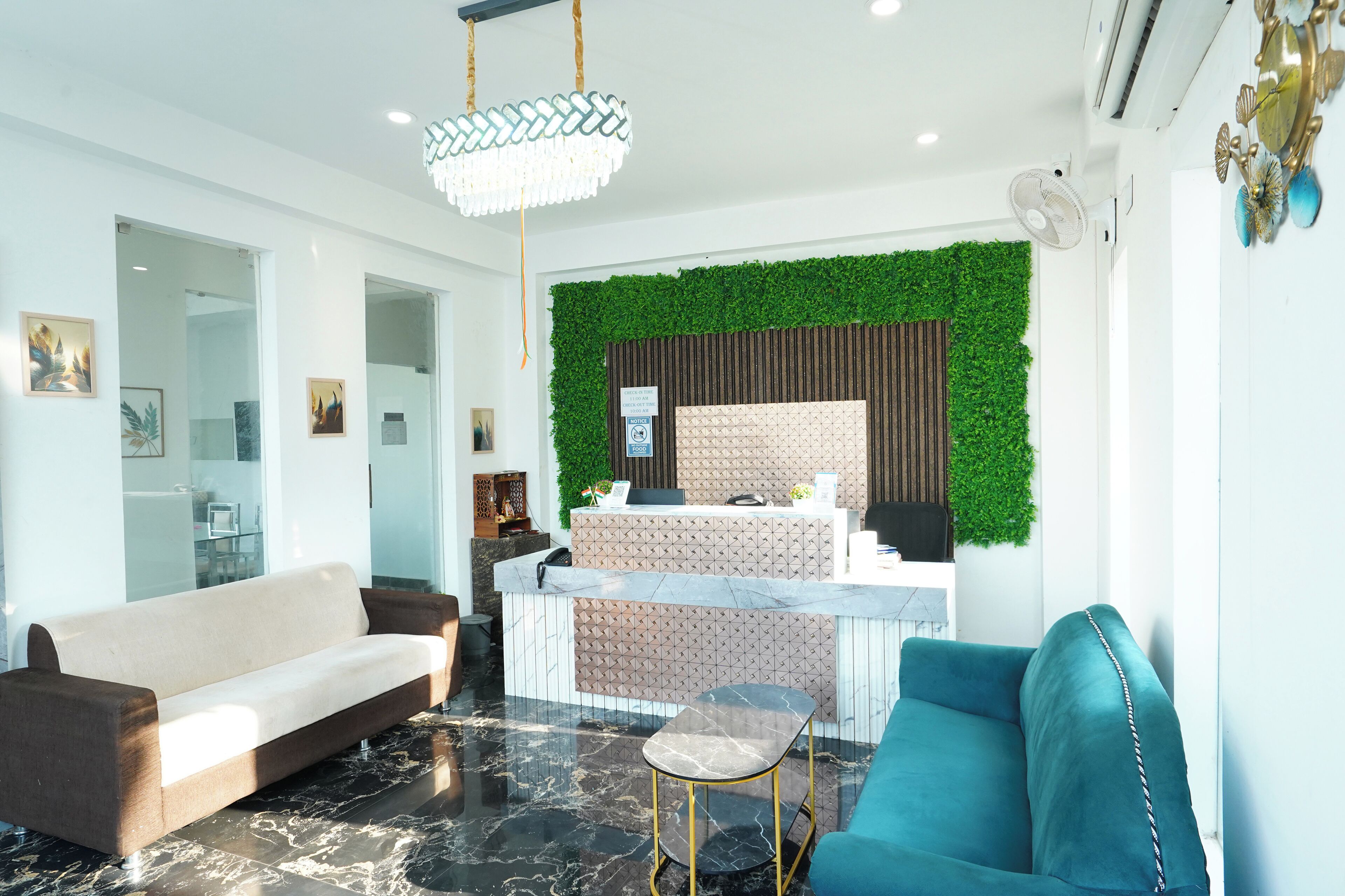 Un área de recepción moderna con una pared verde, un mostrador de recepción, un sofá y una silla.