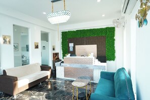 A modern reception area with a green wall, a reception desk, a sofa, and a chair. - Hotel Royal Beach Exotica (Kanthi)