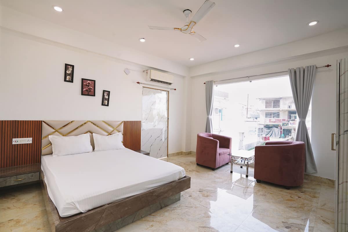 A hotel room with a bed, a ceiling fan, a window with curtains, and a view of the outside.
