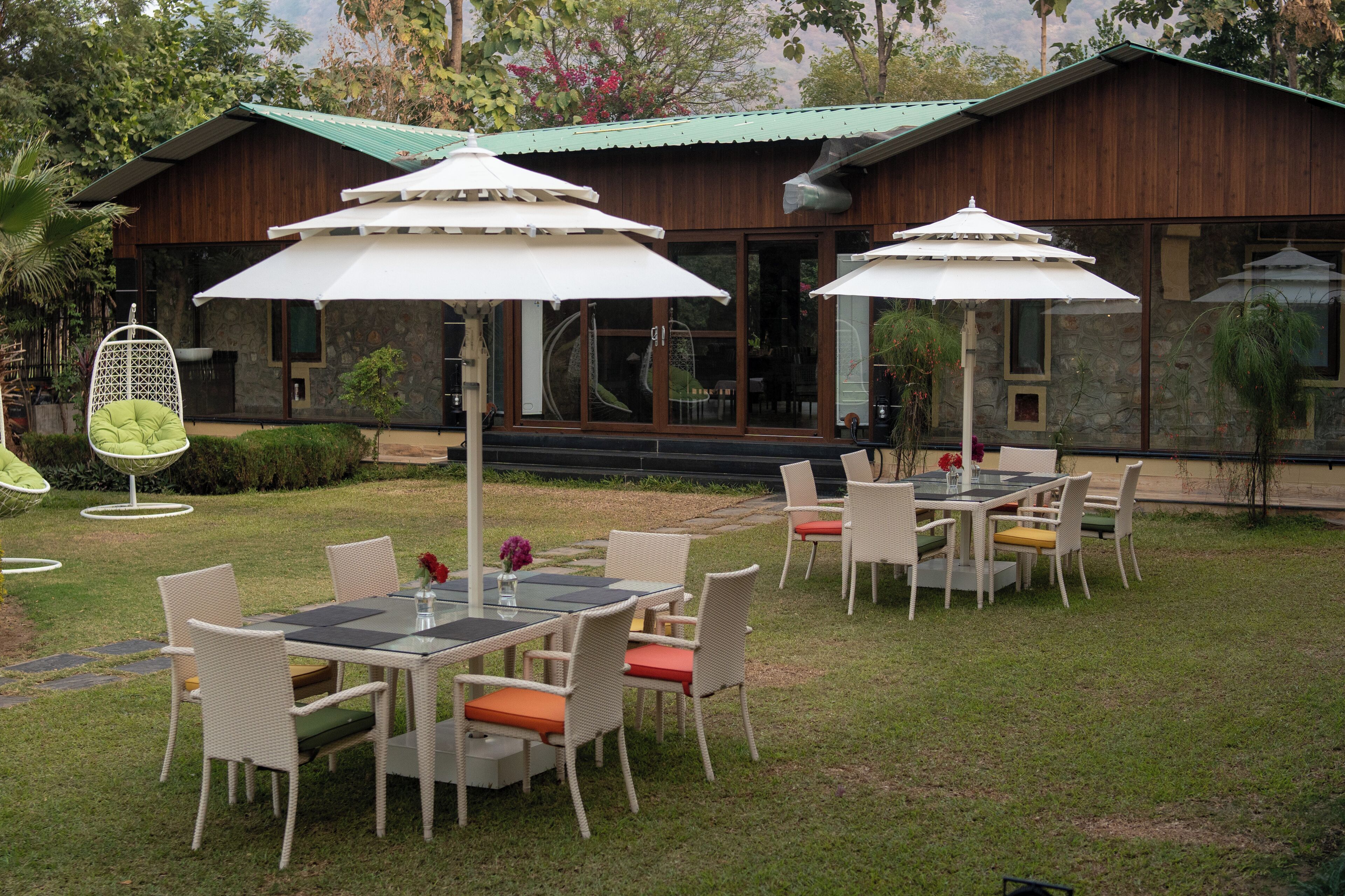 An outdoor seating area with tables and chairs, surrounded by a wooden building with large windows.