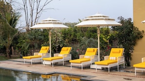 A poolside area with lounge chairs and umbrellas. - The Farm Stay by Aamaghati (Sawai Madhopur)