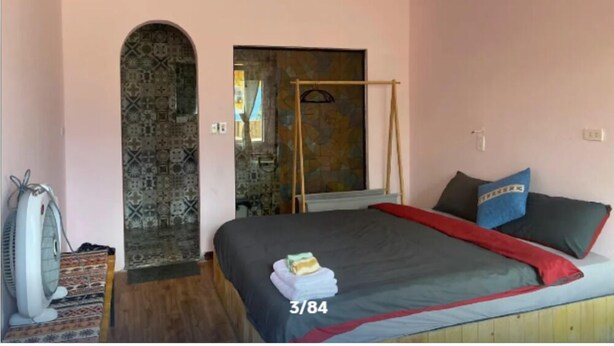 A bedroom with a bed, a fan, a shower area, and a patterned wall. - D Home Sapa 8 (Sa Pa)
