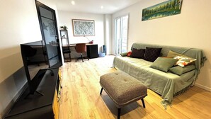 En kompakt opholdsstue med sofa, skrivebord, stol og fjernsyn.