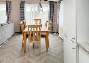A modern kitchen with a dining table, chairs, and a sofa.