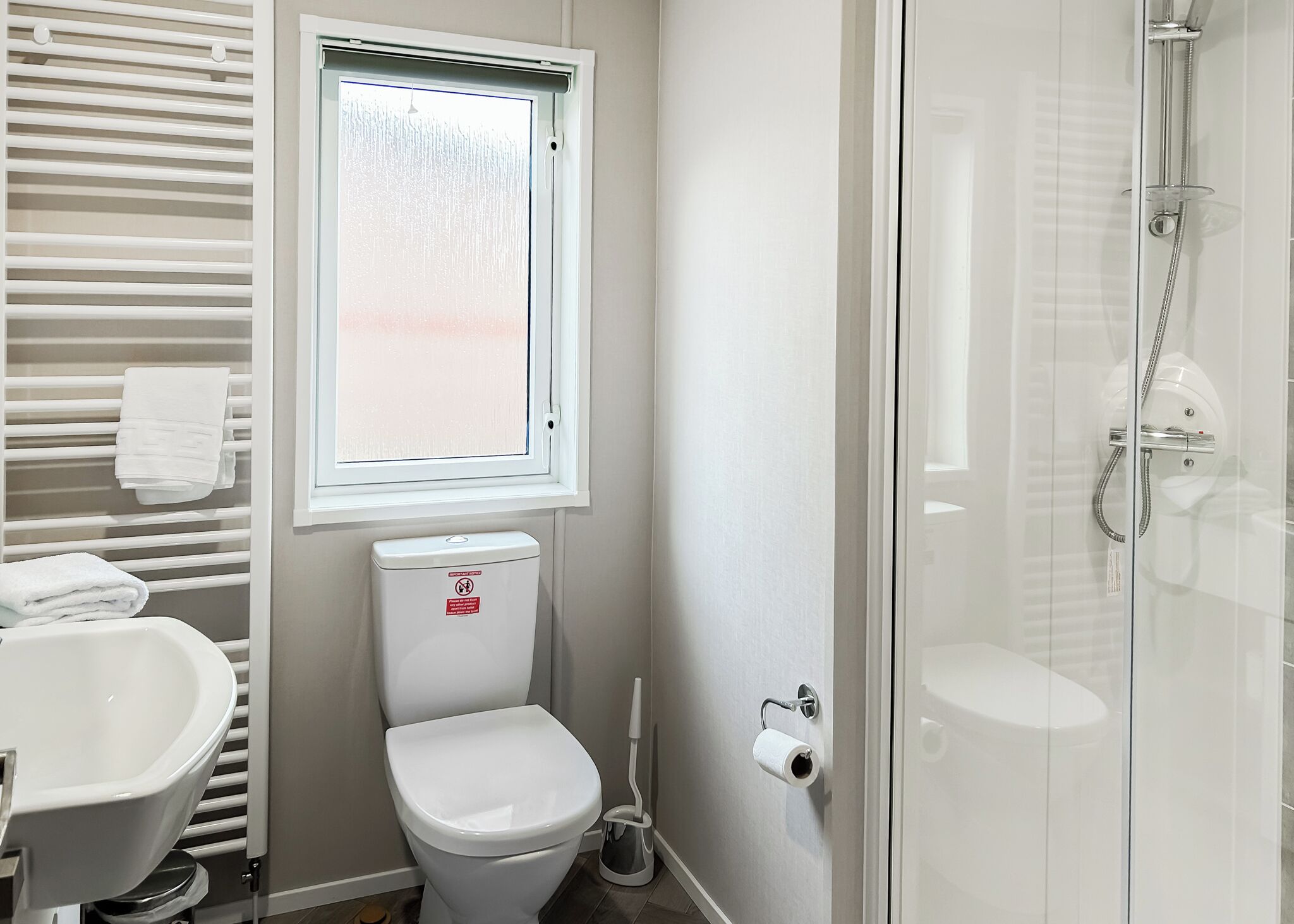 Een badkamer met toilet, hygiëneschuimer en douche.